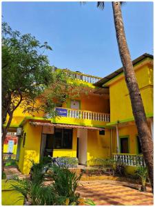 a yellow house with a palm tree in front of it at Palash Villa in Aguada