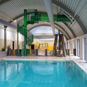 a swimming pool with a green stairway in a building at Vakantiepark Koningshof in Rijnsburg