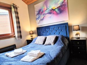 a bedroom with a blue bed with towels on it at Kingfisher Lodge-HuntersMoon -Warminster-Longleat-Bath in Warminster
