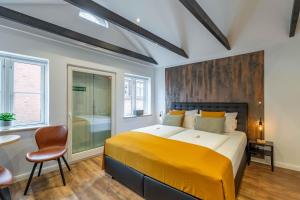 a bedroom with a large bed with a yellow blanket at LÜTTES LOFT Boutique Hotel in Eckernförde