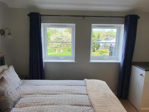 a bedroom with two windows and a bed in it at River Cottage in Stoke Ferry