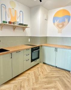 eine Küche mit weißen Schränken und Holzböden in der Unterkunft 3 Waves Apartment Gdansk STARÓWKA- GYM, SAUNA, KidsPlay, PARKING in Danzig