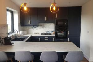 a kitchen with black cabinets and a counter with chairs at Hogan's Cottage in Ennistymon