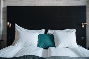 a bed with white pillows and a green pillow at Clarion Hotel Wisby in Visby