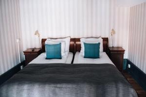 a bedroom with a bed with two blue pillows at Clarion Hotel Wisby in Visby