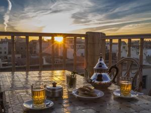 una mesa con comida y bebida en un balcón con vistas a la puesta de sol en Villa Garance, en Essaouira