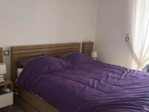 een bed met een paars dekbed in een slaapkamer bij Appartement avec terrasse à 150m de la plage in Calvi