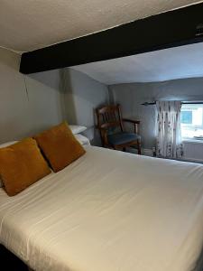 a bedroom with a large white bed and a chair at Black Bull Hotel in Reeth