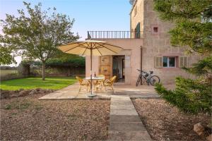 a table and chairs under an umbrella in a yard at Finca Hotel Can Canals & Spa in Campos