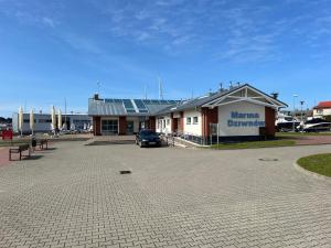 a building with a car parked in a parking lot at Blue marina in Dziwnów