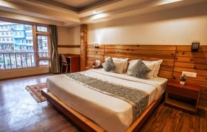um quarto com uma cama grande e uma janela grande em Gangtok Prime Hotel & Spa em Gangtok