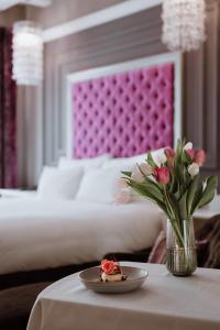 a table with a plate of food and a vase of flowers at Aria Hotel Budapest by Library Hotel Collection in Budapest