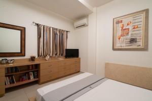 a bedroom with a bed and a dresser and a television at Central SeaView Heven Apartment in Fira Santorini in Fira