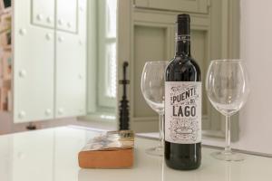 una botella de vino sentada en un mostrador con dos copas de vino en SevillaHome- Altozano Triana en Sevilla