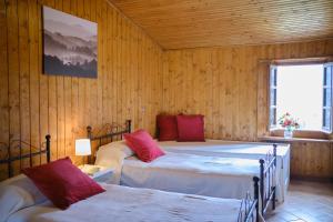 Stazzema的住宿－Il Frutteto Natura a Relax，一间带两张床铺的卧室,位于带木墙的房间内