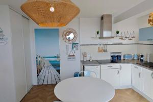 eine Küche mit weißen Schränken und einem Tisch in der Unterkunft BERCK Beach Attitude 160 QUEEN SIZE très confort - 3min de la plage in Berck-sur-Mer