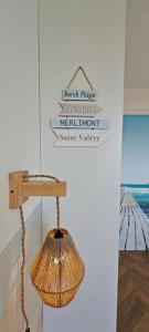 ein Rattanlicht, das an einer Wand hängt, mit Zeichen in der Unterkunft BERCK Beach Attitude 160 QUEEN SIZE très confort - 3min de la plage in Berck-sur-Mer