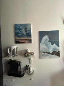 uma prateleira com um micro-ondas e duas pinturas numa parede em Chambre d hôte - Bambou em Saint-Maur-des-Fossés