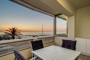Una mesa y sillas en un balcón con vista al mar. en Sundowner Views, en Ciudad del Cabo