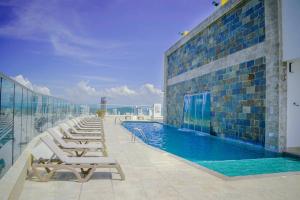 a swimming pool with lounge chairs on a building at Apartament Bocagrande Palmetto Beach Front 3204 in Cartagena de Indias