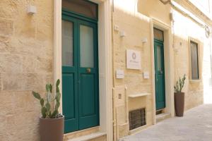 una porta verde sul lato di un edificio con piante di All'1 di Rajno' Relaxing ApartHotel a Lecce