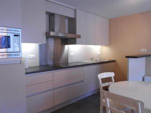 uma cozinha com armários brancos, uma mesa e um micro-ondas em Cezanne app 0501 em Nieuwpoort