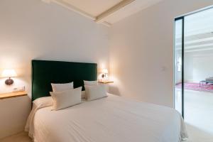 a bedroom with a white bed with a green headboard at AoA Atico Lujo Santa Marta in Seville