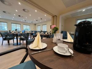 une salle à manger avec des tables, des chaises et un vase dans l'établissement Hotel Drei Kronen Elmshorn, à Elmshorn