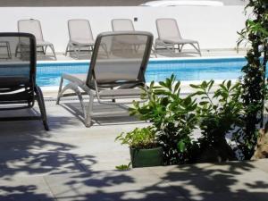 grupa krzeseł siedzących obok basenu w obiekcie Wohnung in Vodice mit Terrasse, Garten und gemeinschaftlichem Pool w mieście Vodice
