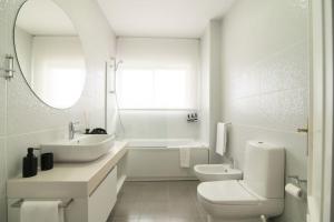 a white bathroom with a sink and a toilet at Cozy Sea View Apartment near City and Airport in Ponta Delgada