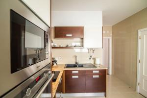 a kitchen with brown cabinets and a sink and a tv at Cozy Sea View Apartment near City and Airport in Ponta Delgada
