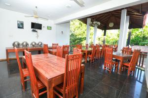 uma sala de jantar com mesas e cadeiras de madeira em Yala Freedom Lodge em Tissamaharama