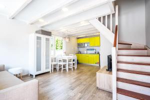 a kitchen and dining room with yellow cabinets and a staircase at Bedroom - domek nr 1 in Łeba +6 photos