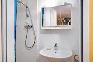 a white bathroom with a sink and a shower at Milchtütenzimmer - Upcycling in Grünwald