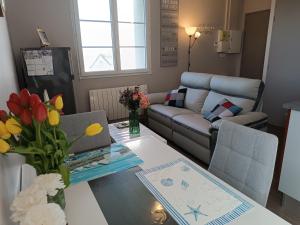 sala de estar con sofá y mesa con ordenador portátil en Appartement Cosy proche Mer en Gouville-sur-Mer