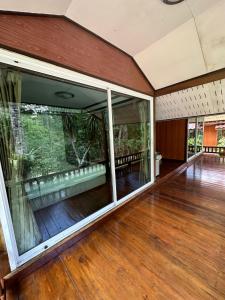 an empty house with large glass windows and a wooden floor at ท่าเเพ รีสอร์ท in Ban Tha Phae