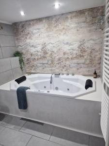 a white bath tub in a bathroom with a stone wall at For You Apartments Gold & Silver in Sibiu