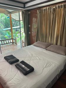 a bed with two black towels on top of it at ท่าเเพ รีสอร์ท in Ban Tha Phae