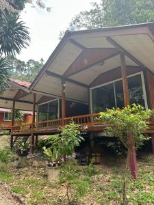 a house with a large wooden deck in the yard at ท่าเเพ รีสอร์ท in Ban Tha Phae