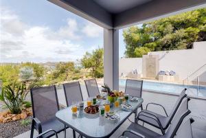 a table and chairs on a patio with a view of a pool at Articiano Villa in Faliraki