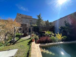 a garden with a building and a swimming pool at Apartamento en Casa del Siglo XVI con caballos in Ametlla
