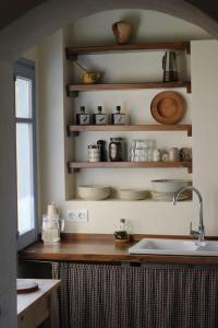 a kitchen with a sink and shelves with dishes at Apartamento en Casa del Siglo XVI con caballos in Ametlla