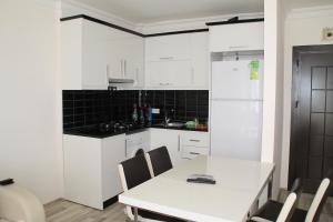 マフムトラールにあるAygun Apartの白いキャビネット、白いテーブルと椅子付きのキッチン