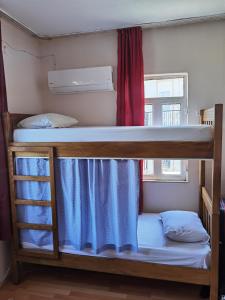 Adventurous Local Hostel في فتحية: سريرين بطابقين في غرفة مع نافذة
