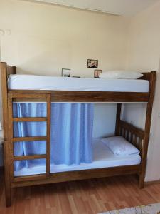 Adventurous Local Hostel في فتحية: سريرين بطابقين مع ملاءات بيضاء وستائر زرقاء