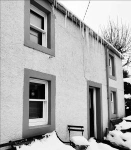a building with snow on the ground in front of it at Pitcaithly Cottage in Abernethy