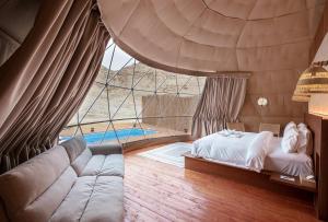 PAUSEAWAY at Tuwaiq House في الرياض: غرفة معيشة مع سرير ونافذة كبيرة