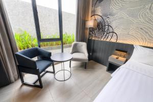 een hotelkamer met een bed, een stoel en een tafel bij ASTON Sorong Hotel & Conference Center in Sorong