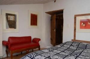 a bedroom with a bed and a red chair at Das spezielle Ferienhaus Heidi - b48536 in Maienfeld