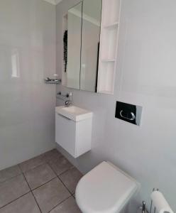a white bathroom with a toilet and a mirror at @946 in Pretoria